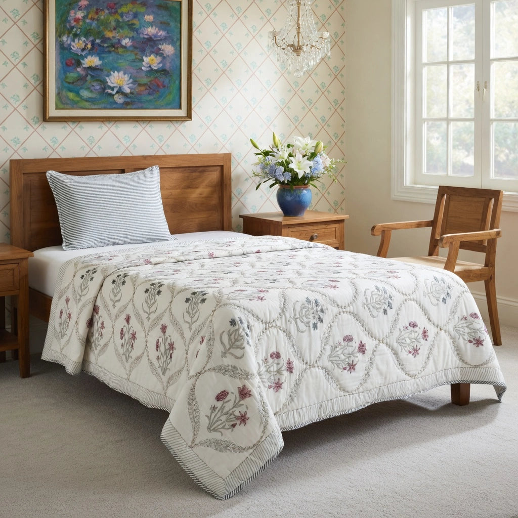 A quilted white bedding set with a floral and geometric pattern, styled on a wooden bed in a bright, classic bedroom.