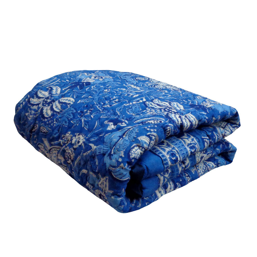 A folded blue quilted comforter with a white paisley and floral pattern, shown on a plain white background.