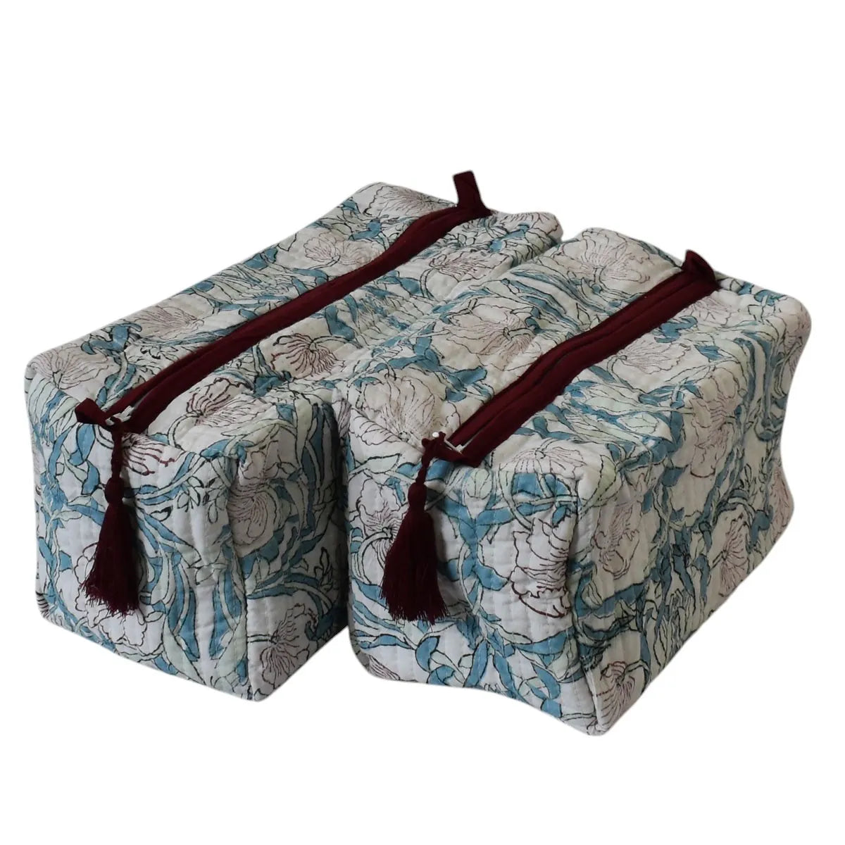 Two rectangular padded support blocks with a blue and beige floral pattern, featuring dark red straps and tassels, shown on a white background.
