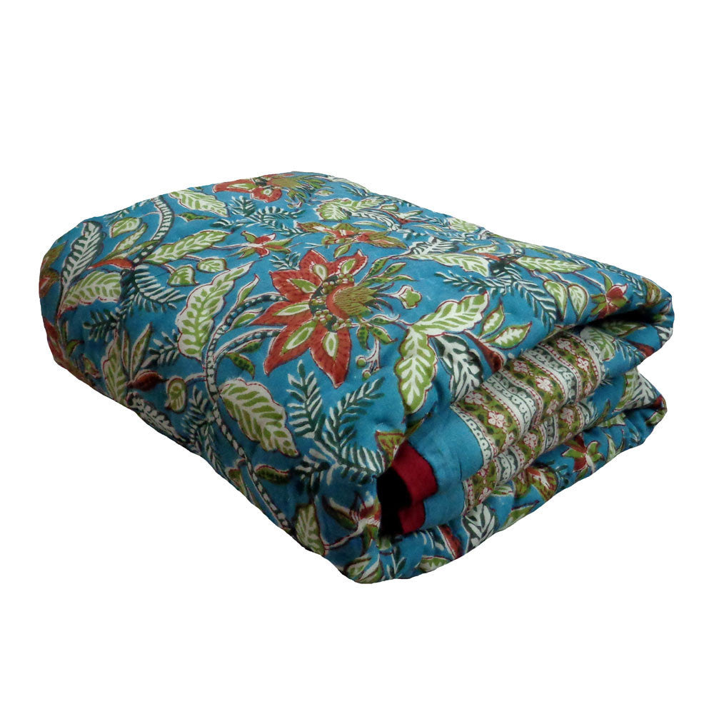 A folded quilted comforter with a vibrant blue base and a detailed multicolor floral and leaf pattern, shown on a plain white background.