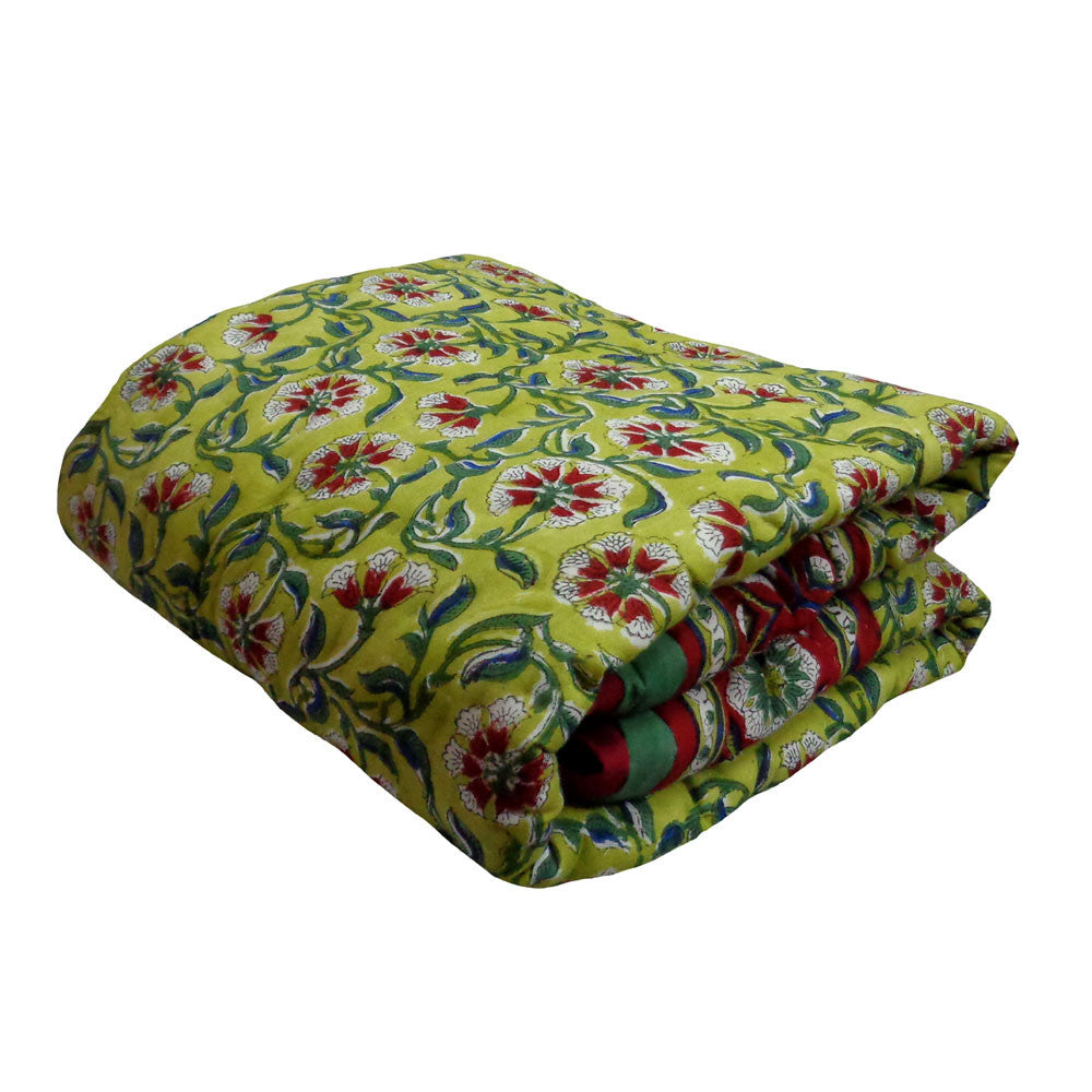 A folded cotton blanket featuring a vibrant yellow-green base with a traditional floral block print in red, white, and green, set against a plain white background.