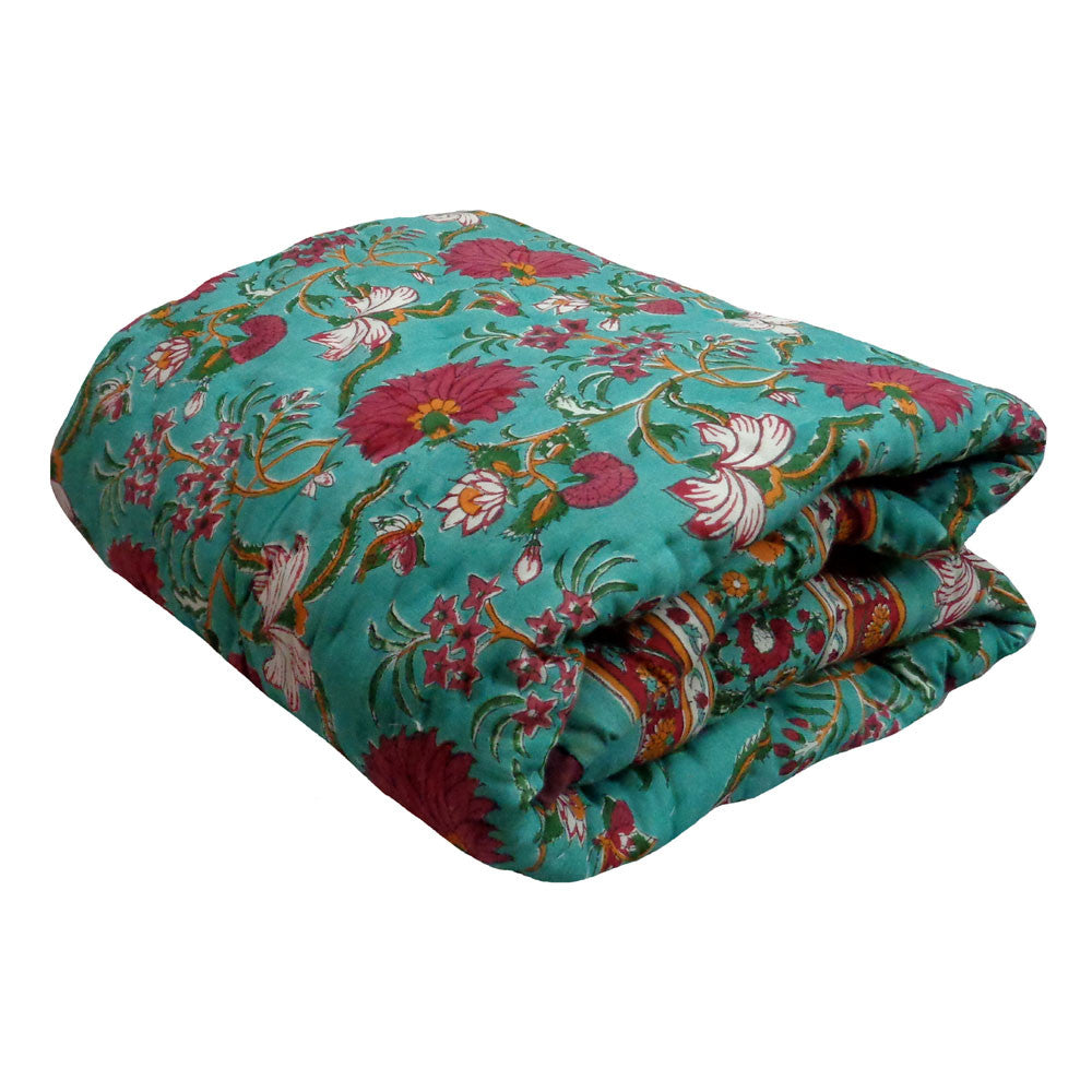 A folded quilted blanket featuring a vibrant teal background with a detailed floral pattern in red, pink, white, and green, set against a plain white background.
