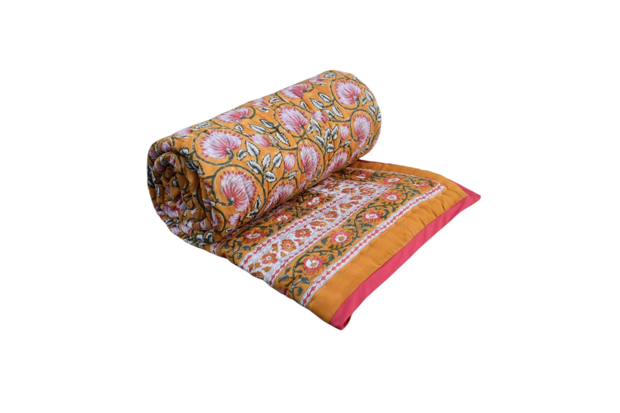 A rolled and partially unrolled patterned quilt or comforter on a plain white background. The fabric features a warm mustard yellow base with intricate pink, orange, and green floral and paisley motifs, finished with a bright pink border.