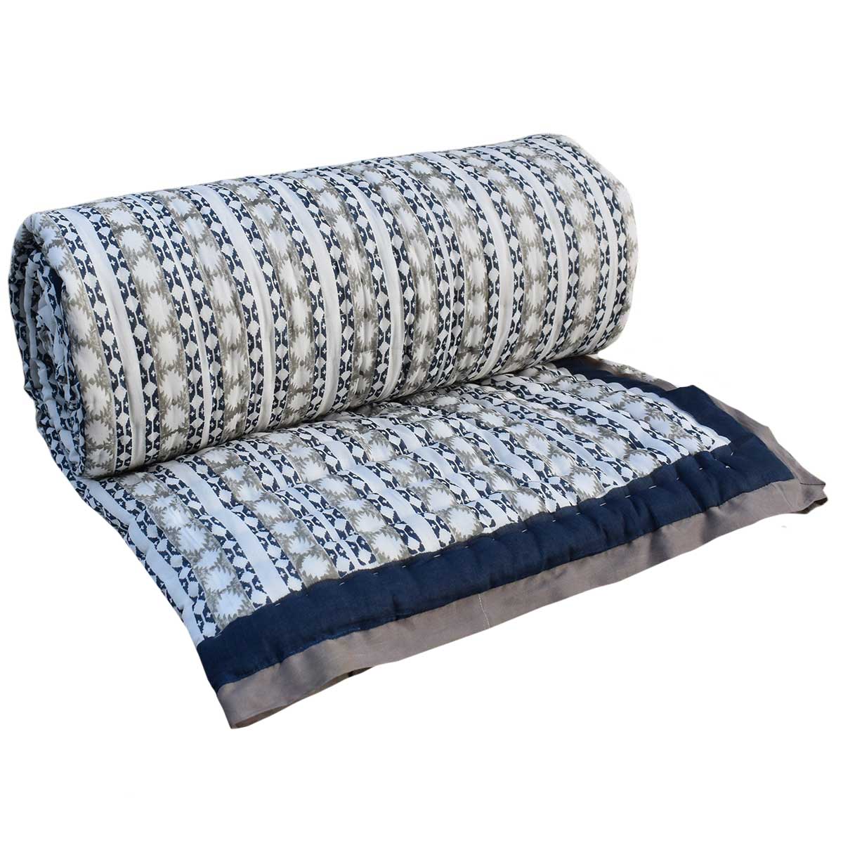 A rolled-out quilted blanket with a geometric pattern in gray, white, and navy blue, featuring a solid navy blue border.