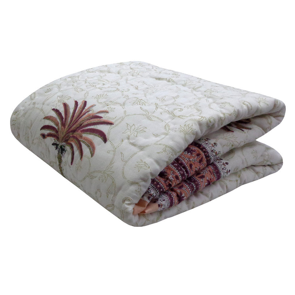 A folded quilted comforter with a light beige floral damask pattern and a brown palm tree motif, showing a patterned red and brown inner side.