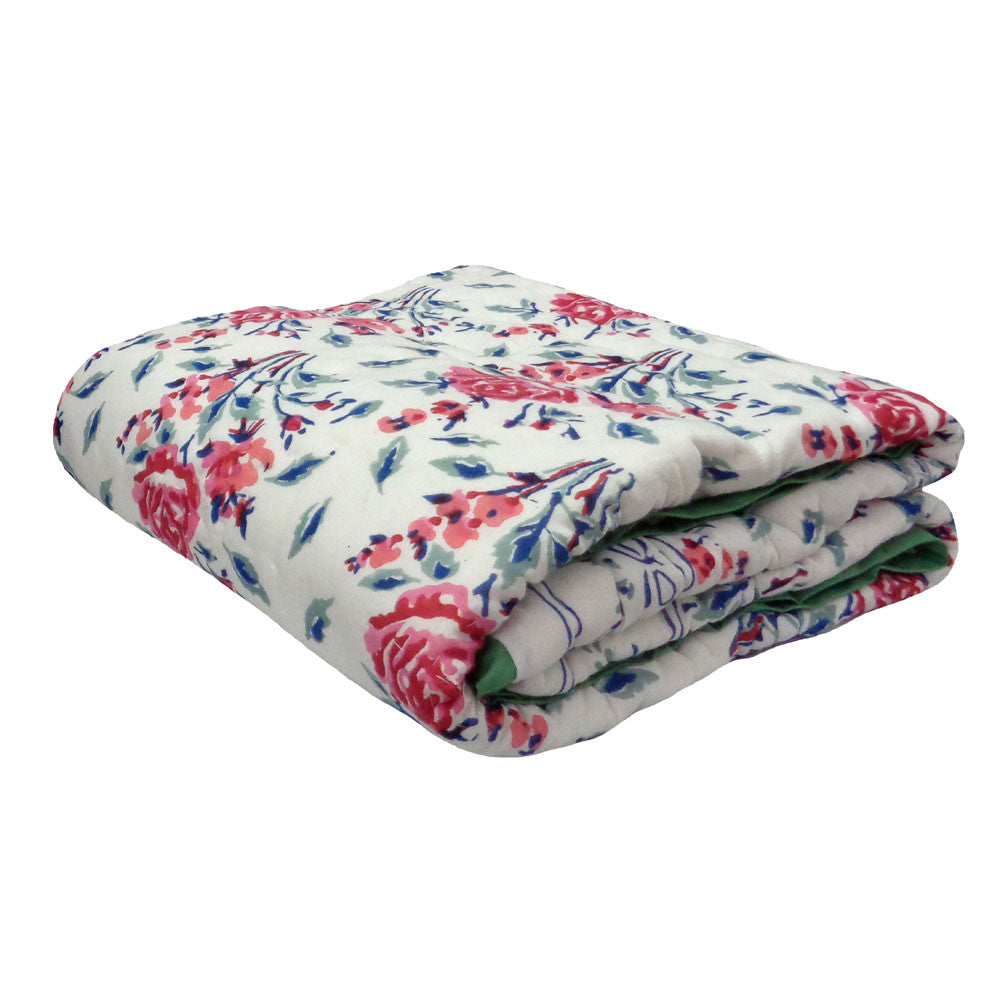 A folded quilted blanket featuring a vibrant floral pattern with red, pink, and blue flowers on a white background, with a green reverse side visible.