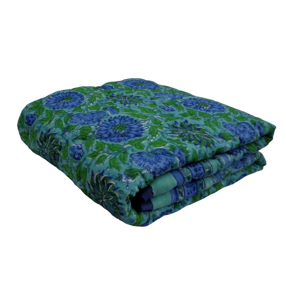 A folded quilted blanket featuring a vibrant blue and green floral pattern, set against a plain white background.